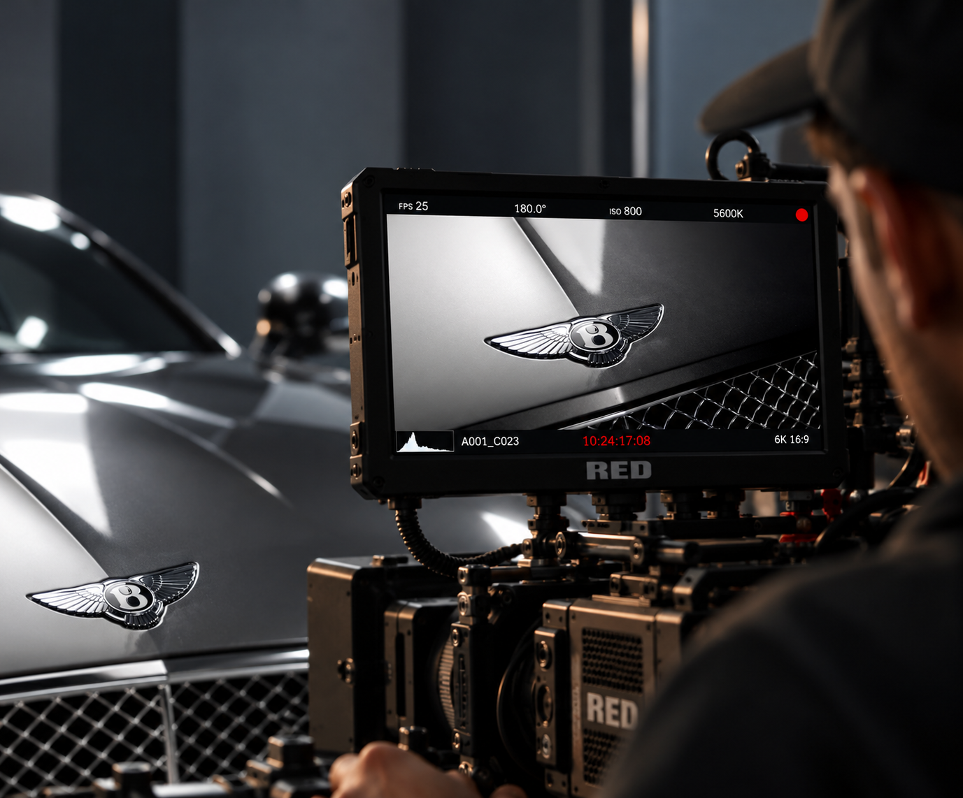 Behind the scenes filming a Bentley, with the car badge framed on a cinema camera monitor
