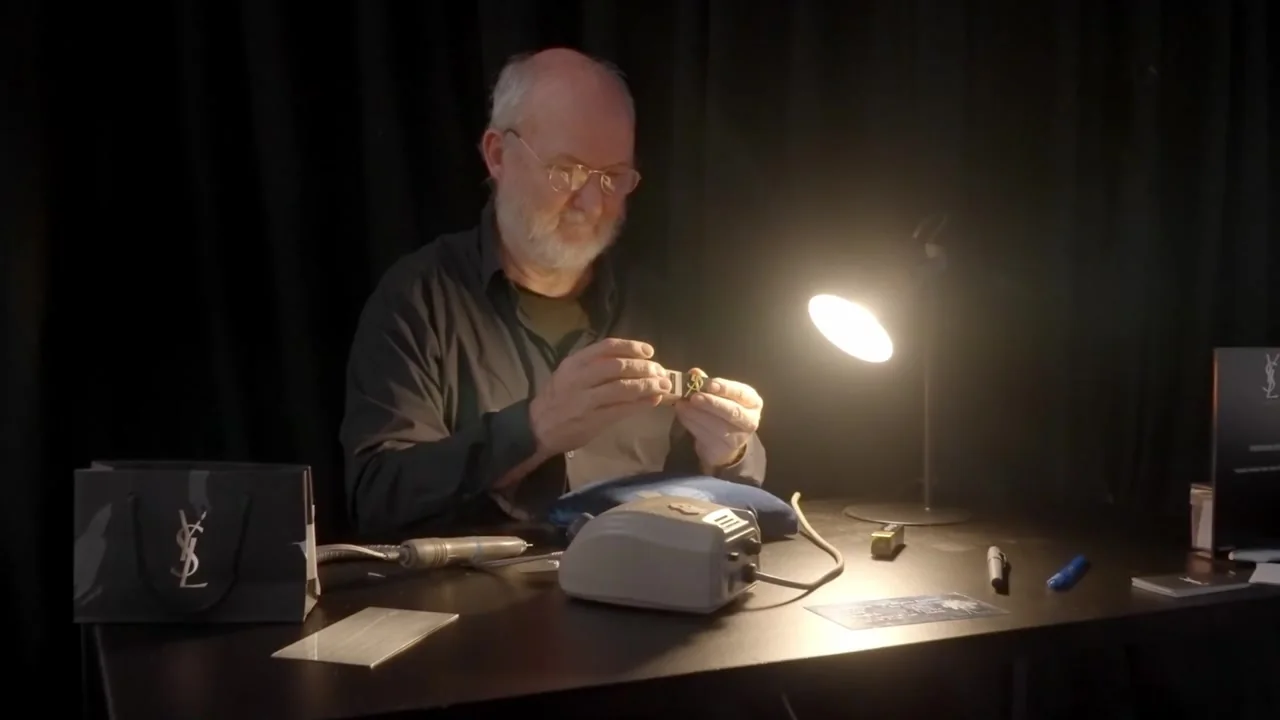 A man working at a table under a warm desk lamp, from the CQ showreel.