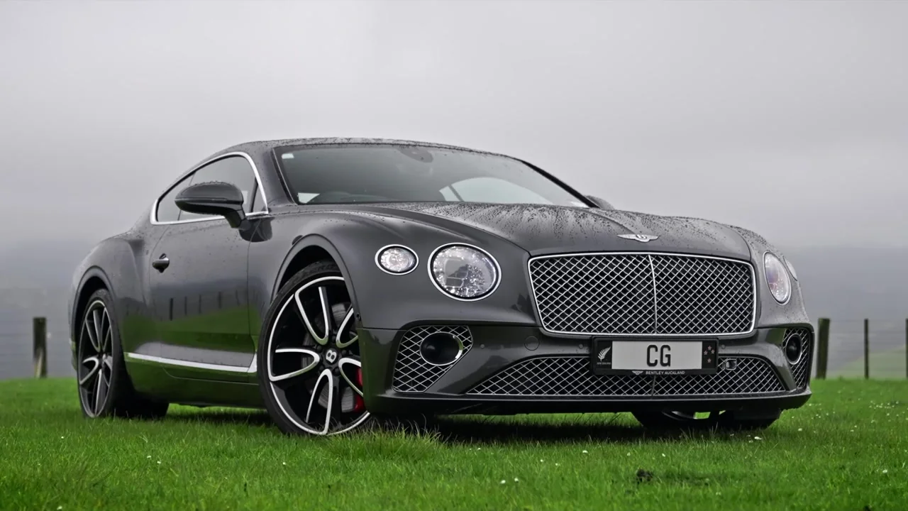 A grey Bentley on green grass overlooking the coast at Parihoa.